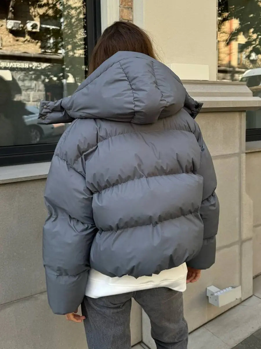 Graue wattierte Pufferjacke mit Kapuze mit isolierendem Design zum Schutz bei kaltem Wetter.
