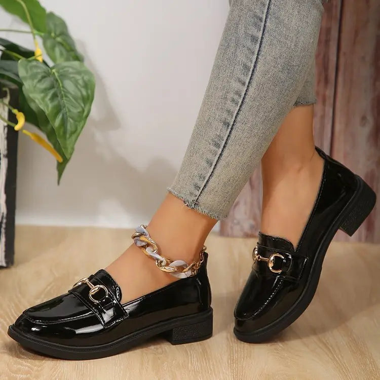 Damen-Lederloafer aus schwarzem Lackleder mit goldfarbenem Pferdebit-Detailing und klobigem Absatz.