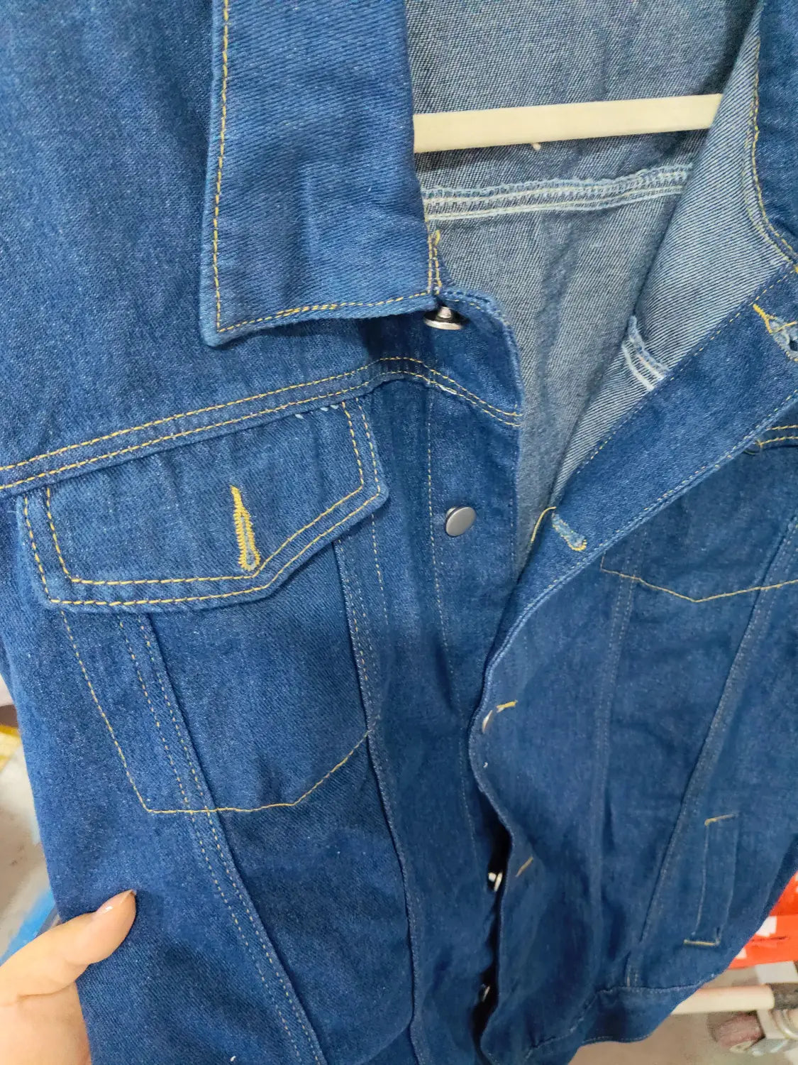 men light wash slim fit denim jacket in blue denim with yellow stitching and silver buttons visible from the front