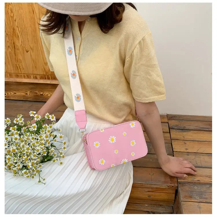 Pink rectangular pu leather crossbody bag with a white strap featuring a pattern of small daisies and a chain strap.