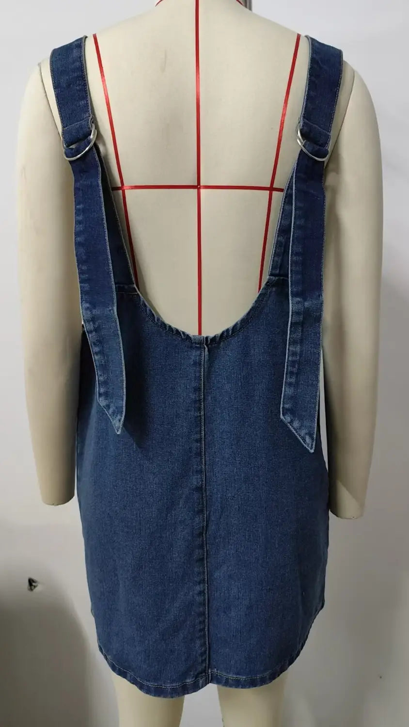vestido peto de mezclilla azul de longitud media con ribete de encaje que presenta tirantes ajustables y un diseño sin espalda mostrado desde el lado posterior