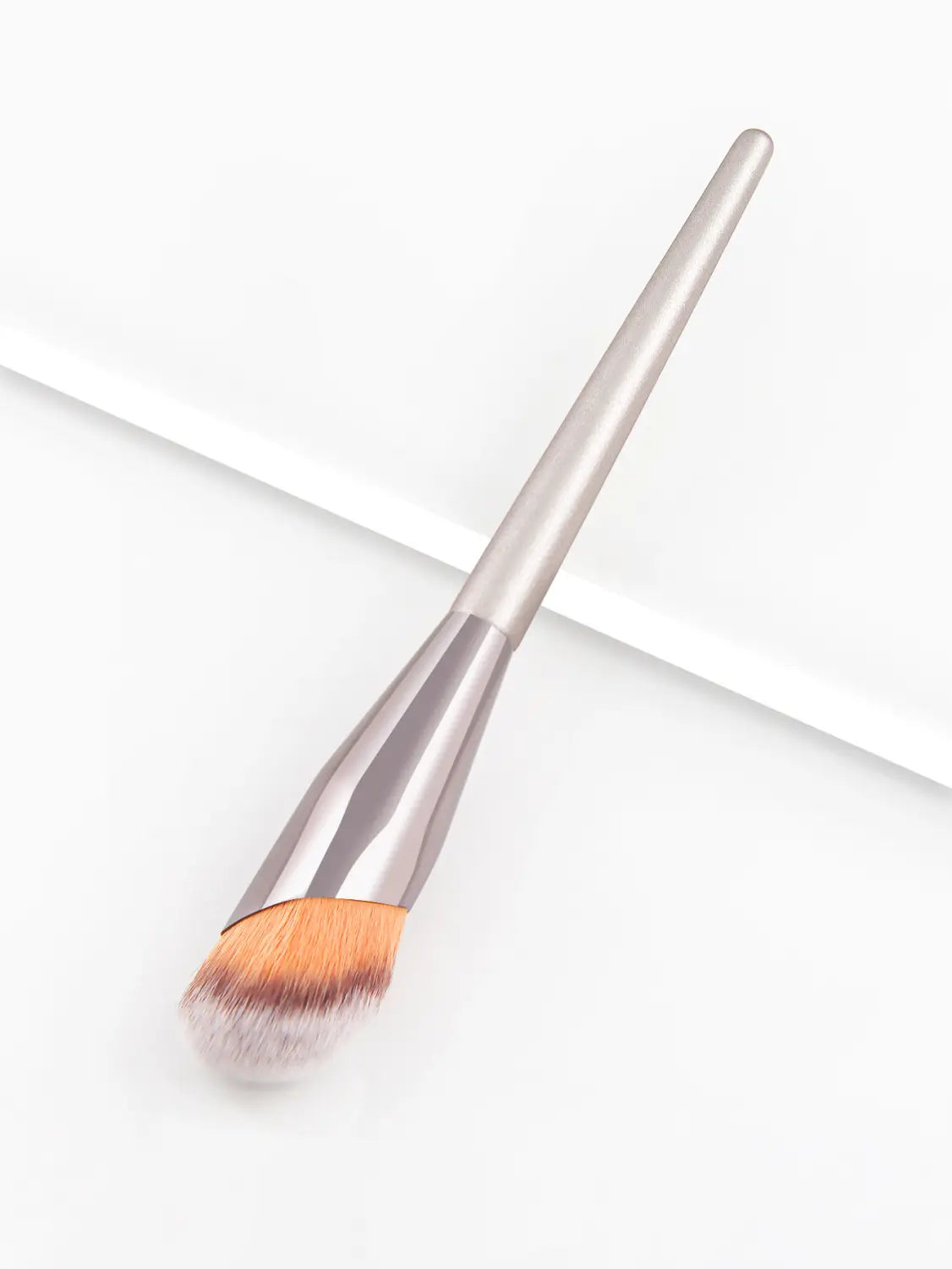 Finger belly makeup brush professional contour tool featuring a silver-toned sleek tapered handle and soft angled bristles in warm orange and brown hues.