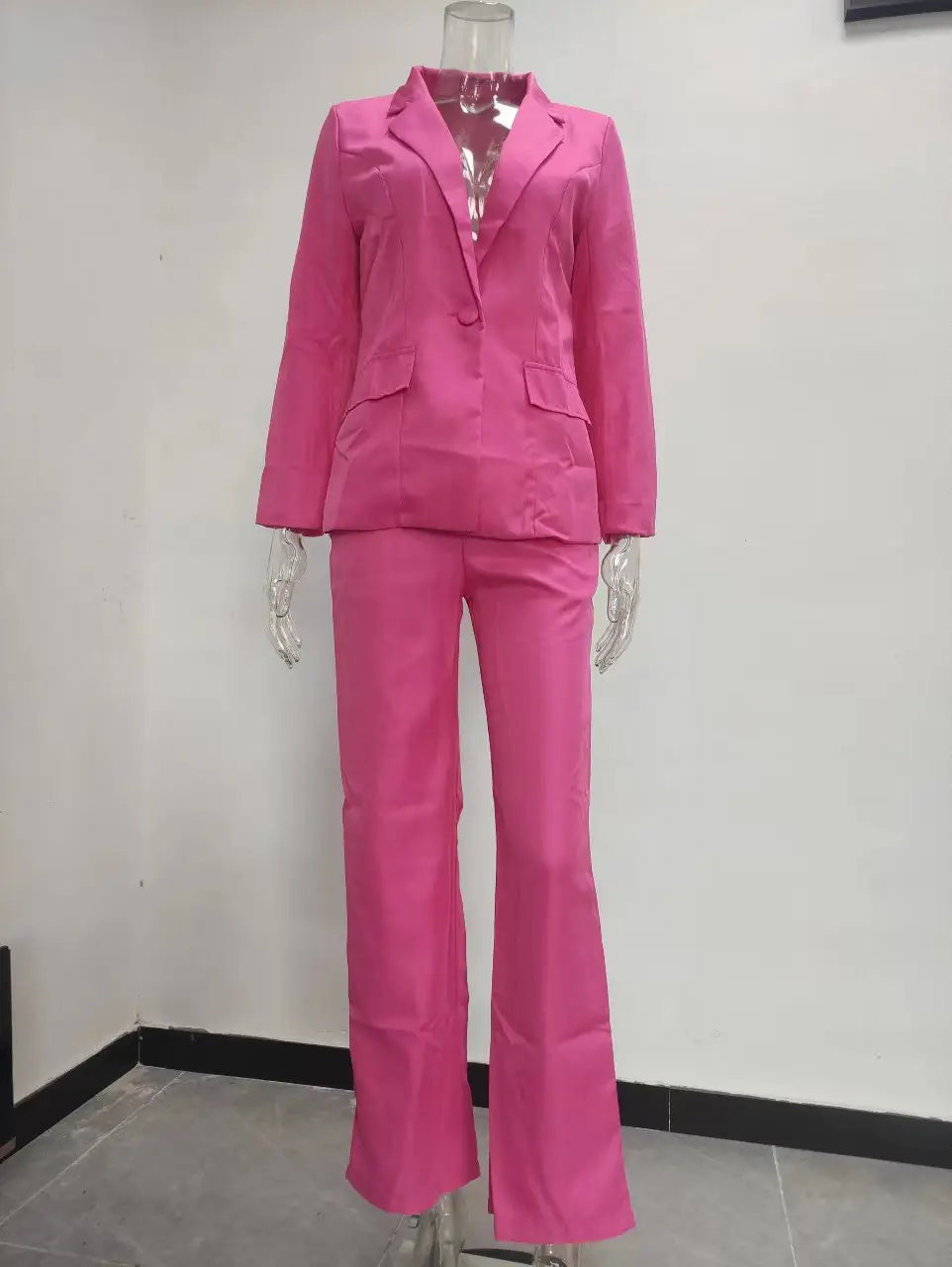 Bright pink women’s tailored blazer and wide leg trouser suit set made of smooth fabric featuring a blazer and flared trousers.