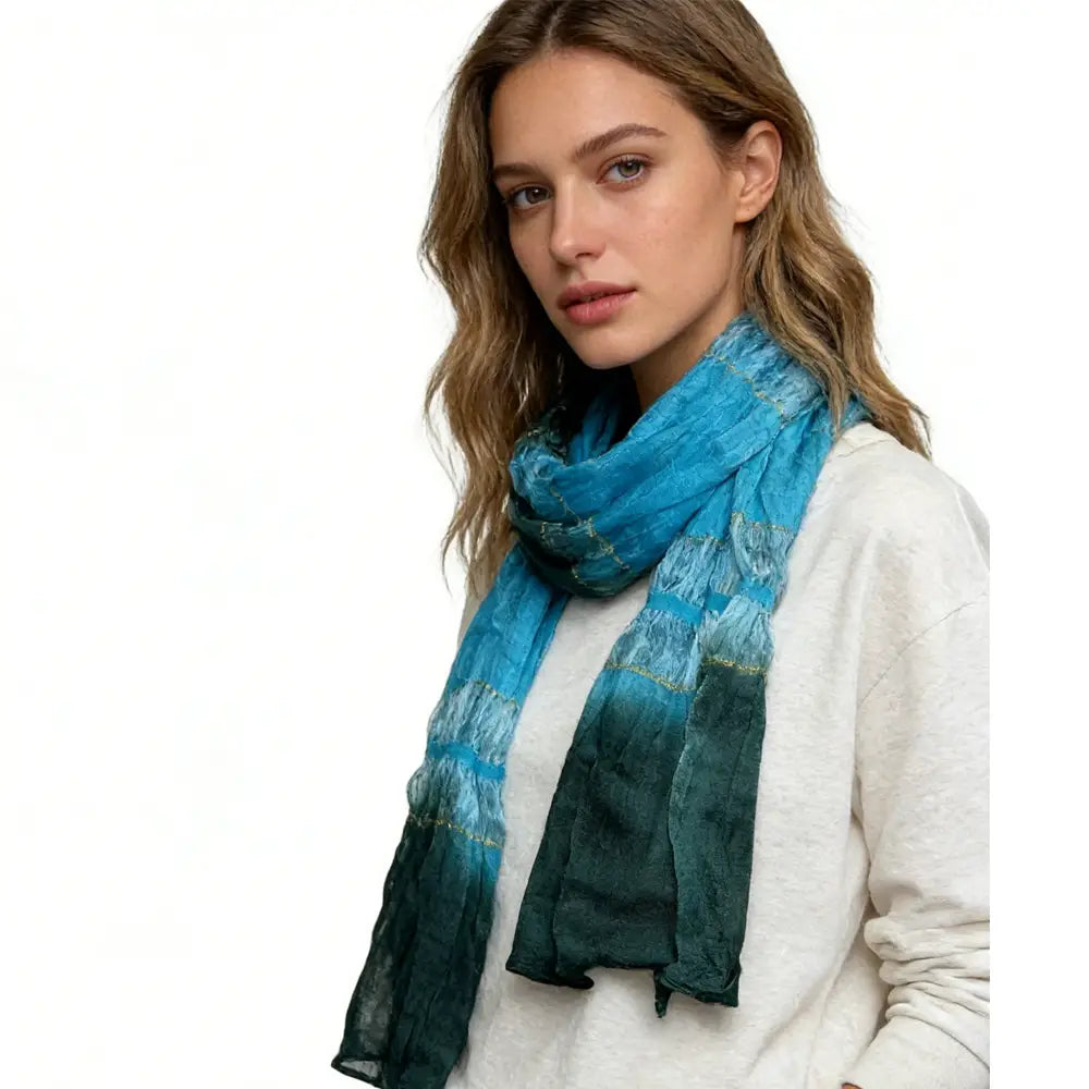 Una bufanda entallada metálica turquesa con un degradado fluido de azul y turquesa con un tejido texturizado sutil.