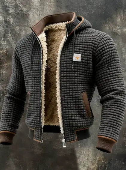 Veste en cuir matelassée doublée en shearling pour homme, en gris foncé, avec bordures marron et une doublure en shearling beige moelleuse, avec patche du logo Carhartt sur la poitrine.