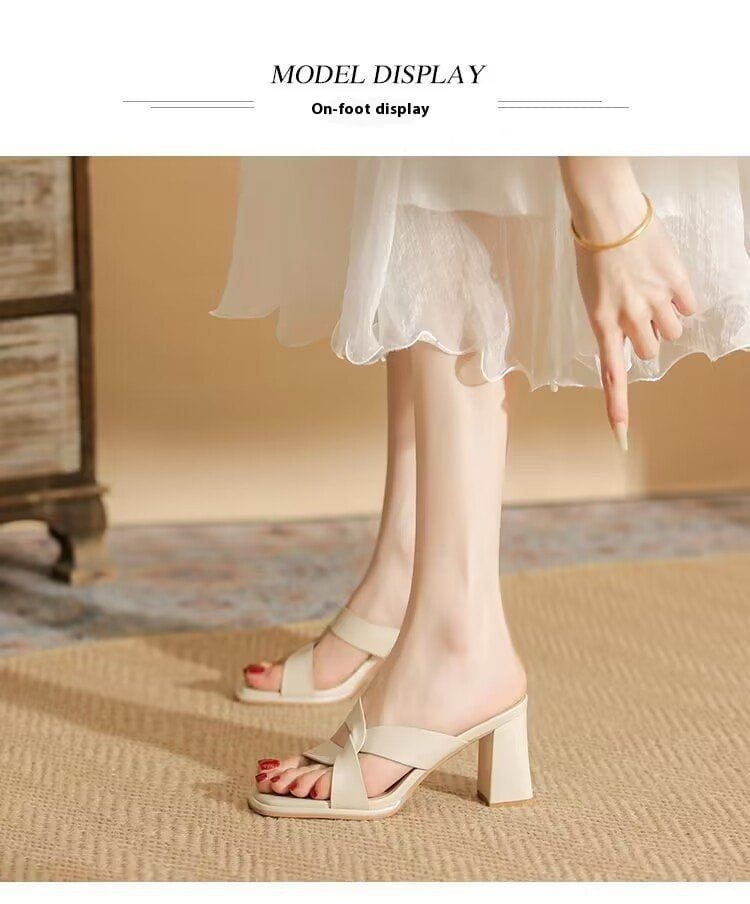 Beige leather-look open toe chunky heel mules with a square heel and crisscross strap design.