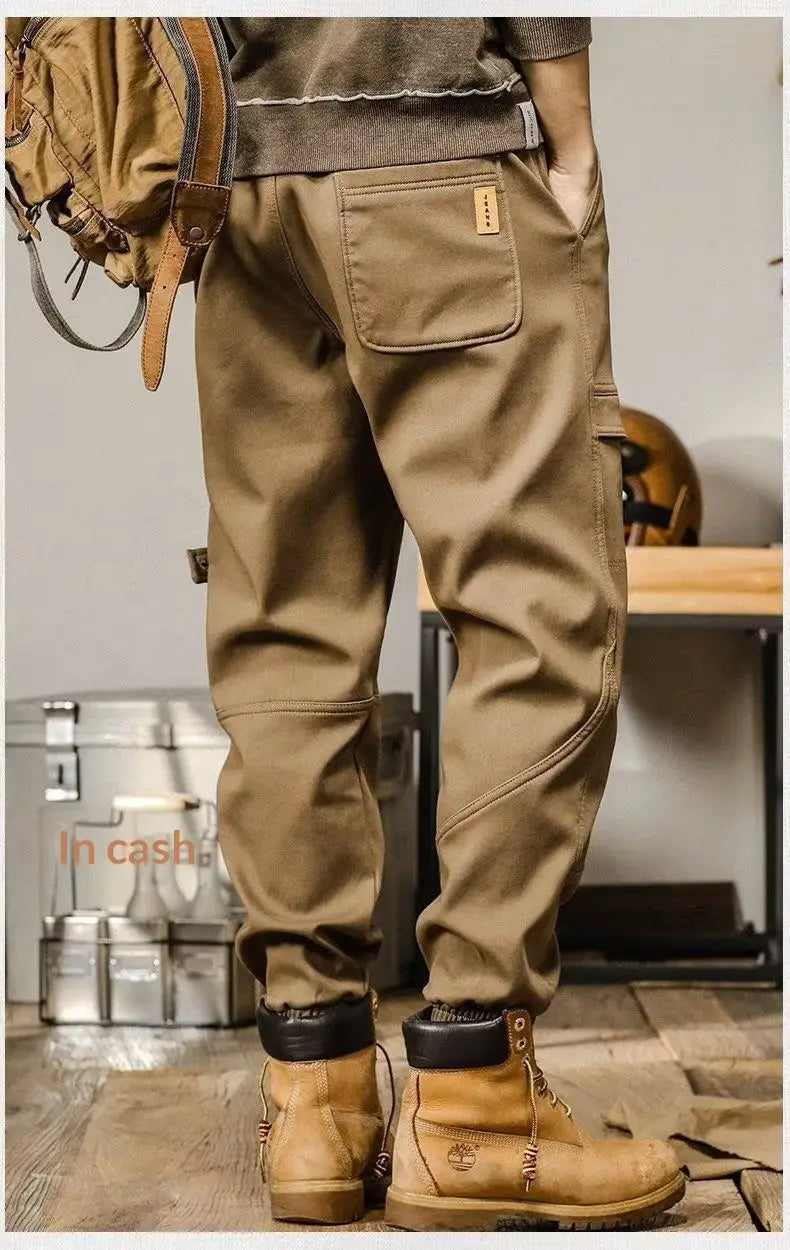 Pantalons cargo pour hommes à coupe ample, style décontracté et vêtement de travail, de couleur tan, avec des coutures renforcées et un petit écusson en cuir sur la poche arrière, présenté depuis le côté arrière