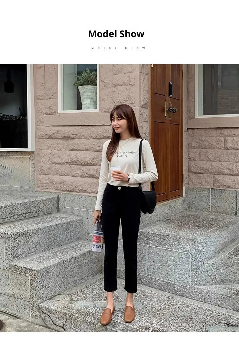 Schwarze Umhängetasche mit schlankem, minimalistischen Design und weichem Material, kombiniert mit schwarzen Samtgefütterten High-Waist-Jeans-Leggings.