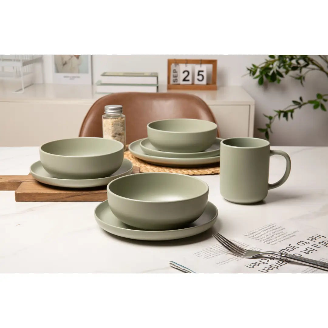 ensemble de vaisselle en grès cérame vert sauge mat, comprenant des assiettes, des bols et une tasse assortie, conçu comme un lot de 12 pièces pour trois personnes.