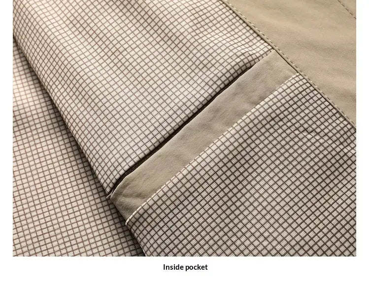 Beige and gray checkered fabric lining with matching beige stitching inside the pocket of a men lapel utility jacket checkered lining.