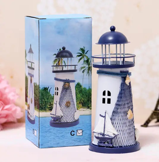 Mediterranean lighthouse garden statue decor featuring a white body with blue accents and roof, detailed mesh pattern on the side, small window cutout, decorative sailboat base, and seashell embellishments.