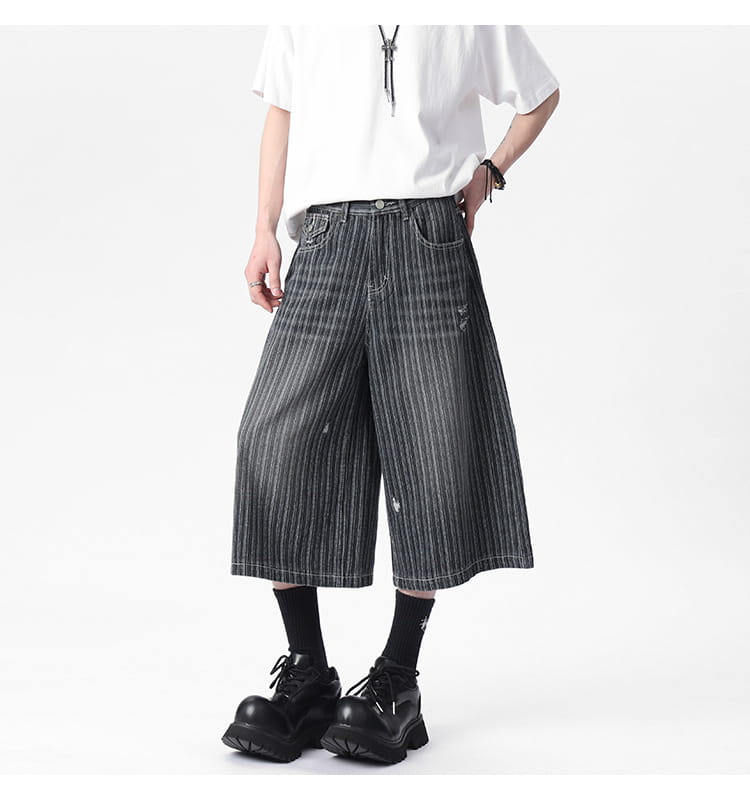 Striped denim capri shorts in black and white vertical stripes with wide-leg fit and distressed details.
