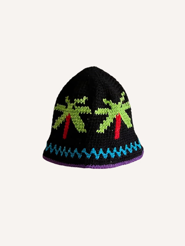 Un chapeau de pêcheur multicolore tricoté à la main noir, orné de palmiers verts éclatants avec des troncs rouges et d’un motif décoratif bleu en zigzag le long du bord, rehaussé d’une bordure violette.