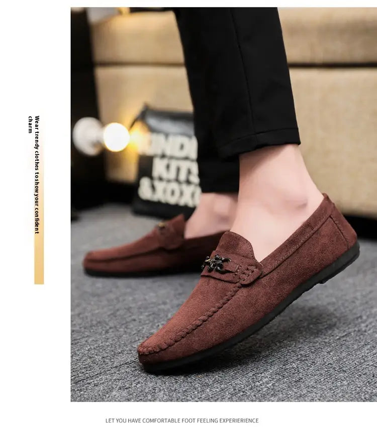 Mocassins à enfiler en daim marron pour homme avec mors de cheval, comportant une boucle métallique décorative sur l’empeigne.