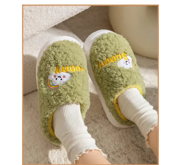 Mint green fuzzy cotton slip-on slippers featuring an embroidered rainbow cloud and auuun text in yellow from the smiling cloud and rainbow plush cotton slippers collection.