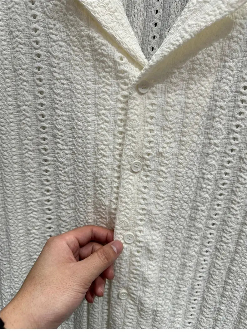 A cream-colored textured knit cardigan with button-front closure and delicate eyelet detailing shown with a men Cuban collar short sleeve shirt.