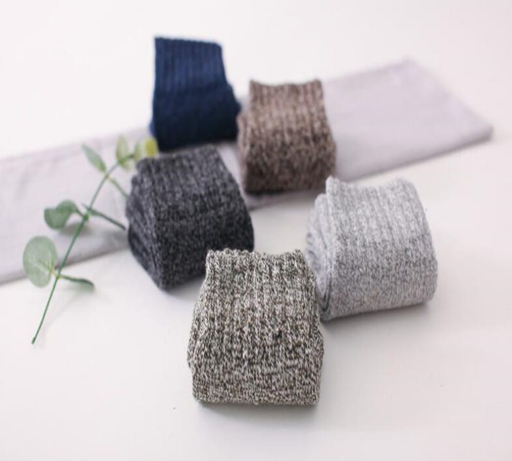 A collection of neatly folded men’s rabbit fur winter socks in textured knit featuring neutral tones of navy blue gray and beige.