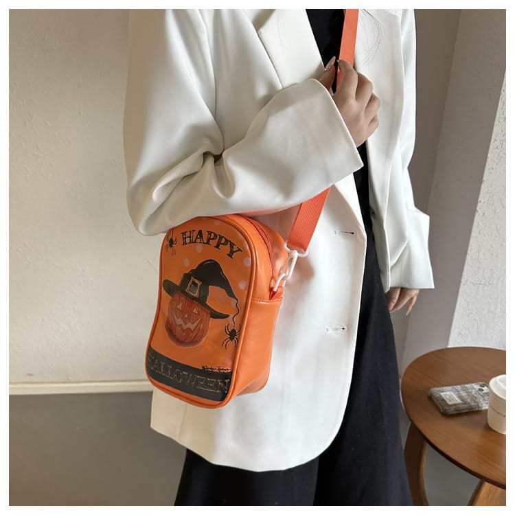 Orange embroidered halloween floral and pumpkin crossbody bag featuring a pumpkin wearing a witch’s hat, black spider details, and happy halloween text in white lettering.