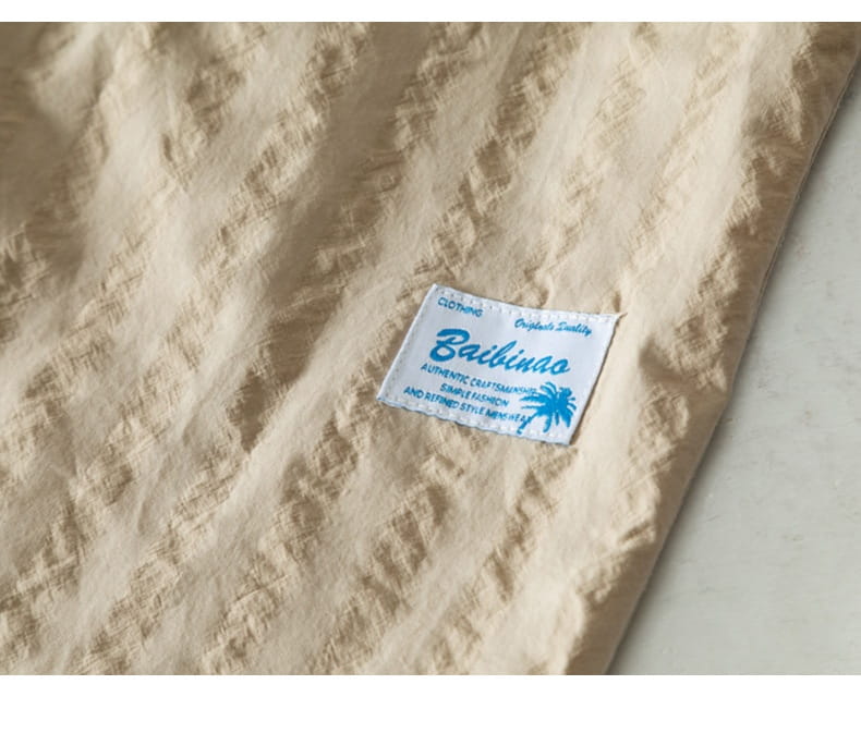 Kurzärmliges Baumwollhemd im lässigen Stil aus beigem, strukturiertem Stoff mit Streifen, mit einem weißen Label mit dem Markennamen bailinoo und einem blauen Palme-Logo.