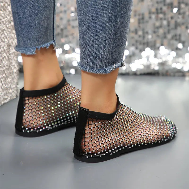 Black mesh slip-on flats featuring sparkling rhinestones along the edges and heel from the rhinestone mesh flat ankle boots for women collection.