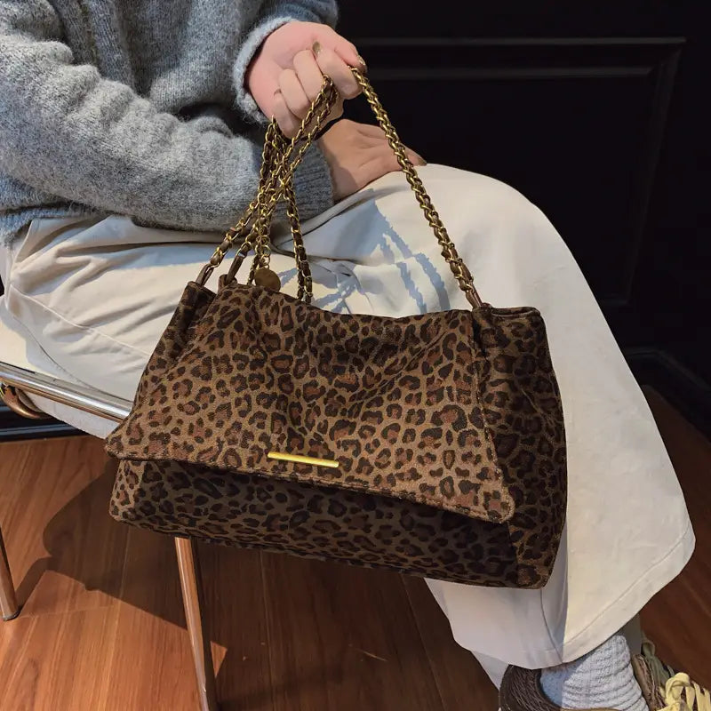 Brown leopard-print velvet crossbody bag with gold-tone chain straps and matching metallic clasp.