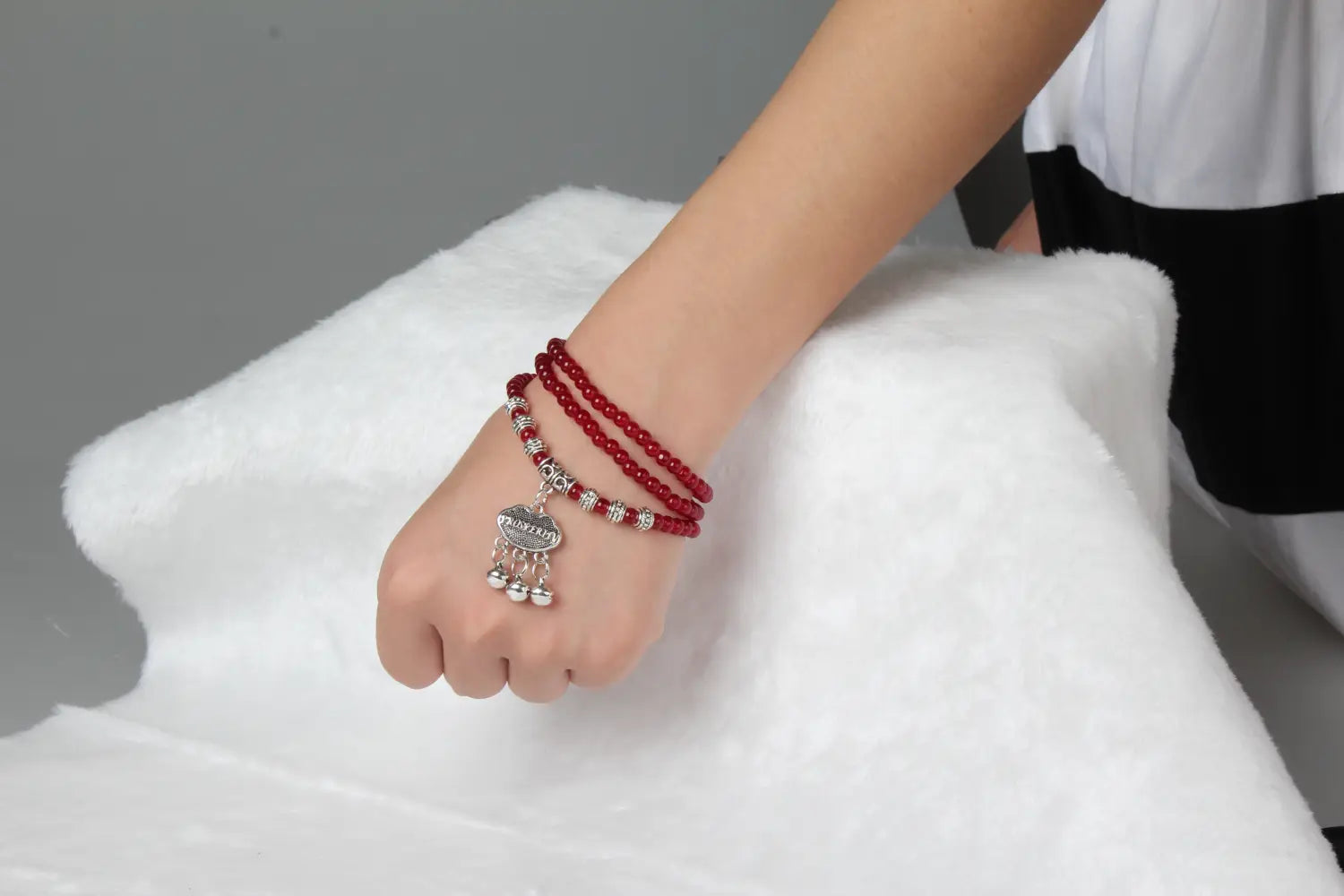 Red agate good luck bracelet featuring red beads with a silver-toned engraved protect charm and dangling bells.