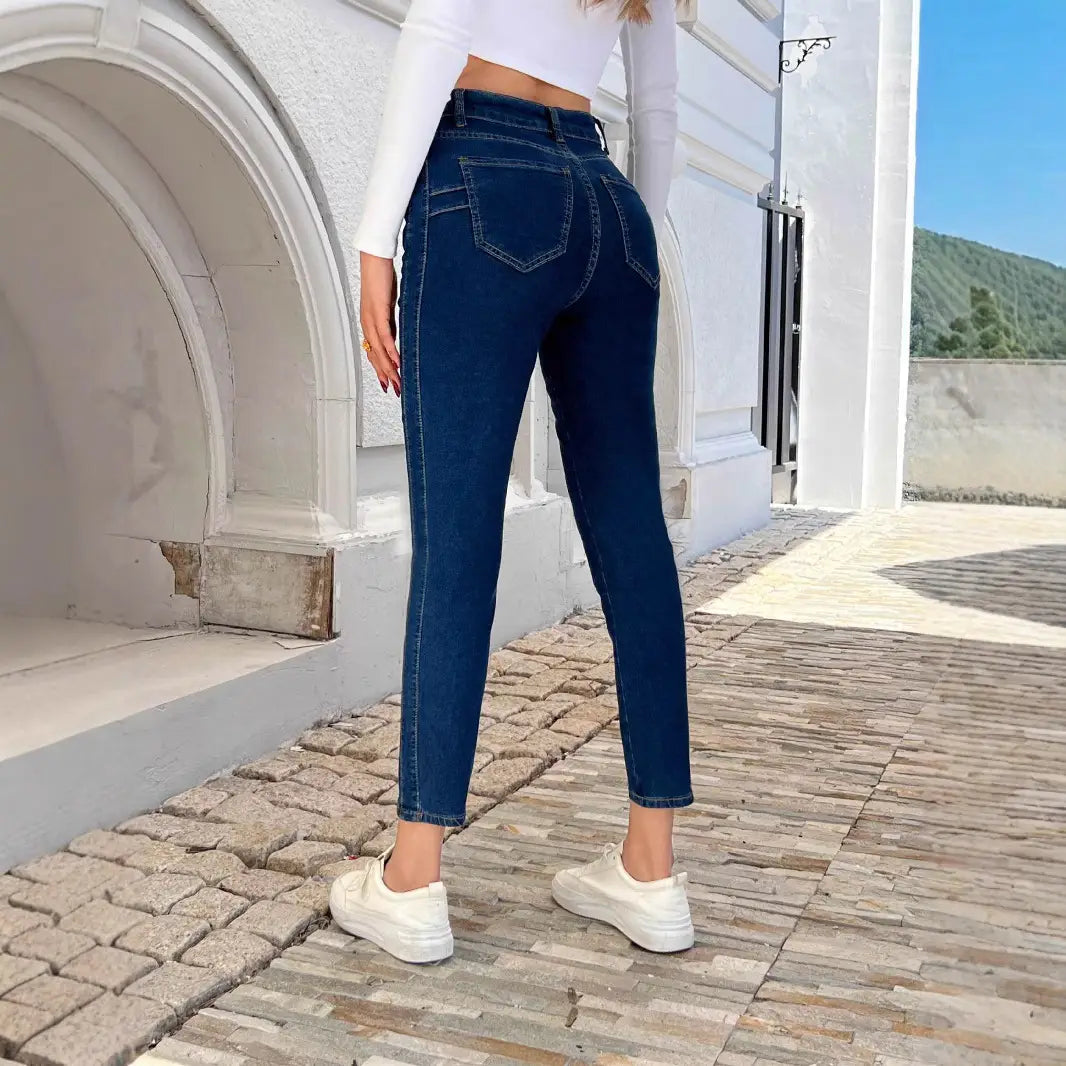 Leggings en jean bleu nuit à taille haute, présentant une texture denim classique et des coutures visibles en coupe ajustée.