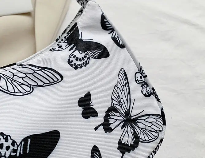 White canvas underarm shoulder bag for women featuring a black butterfly print animal design.