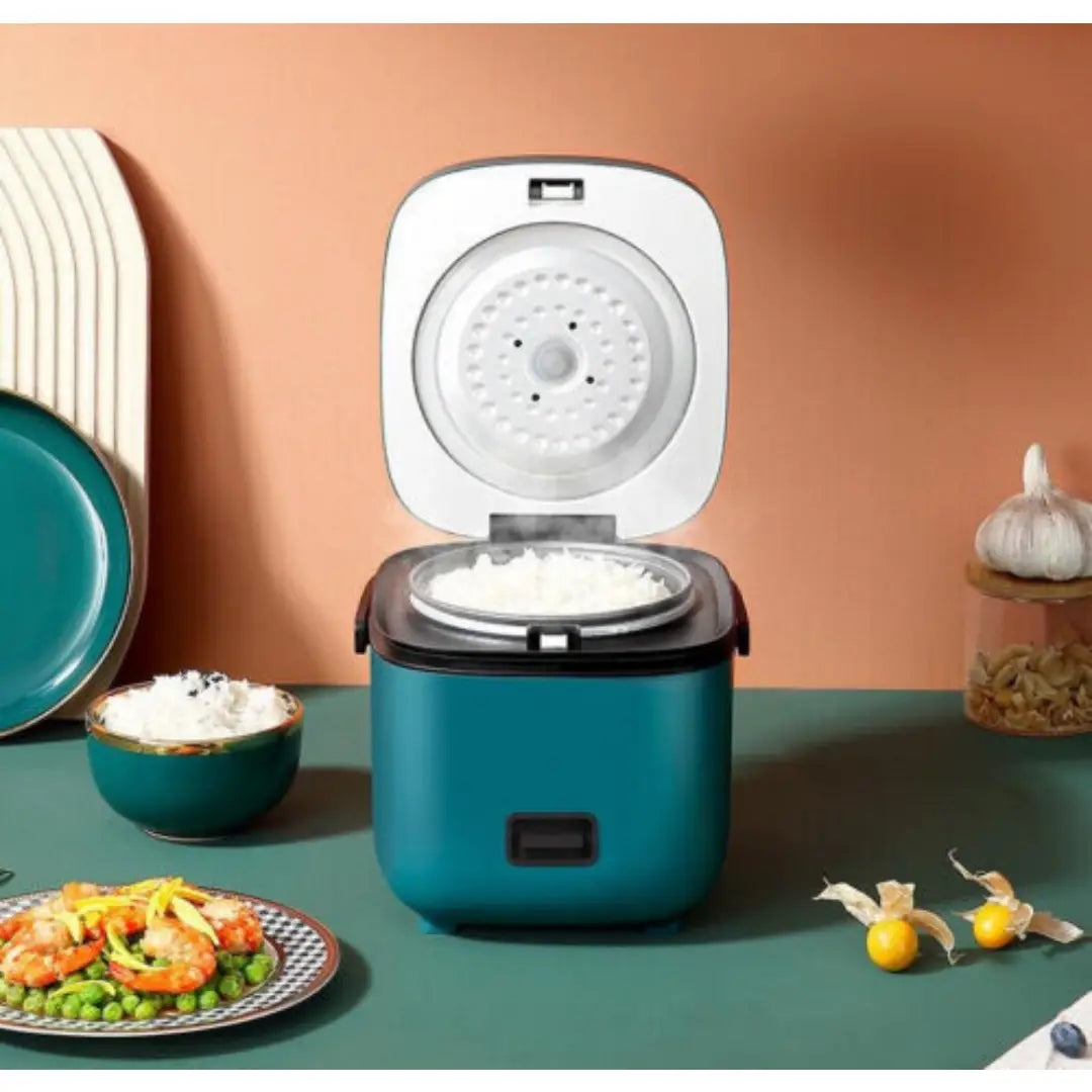 Cocotteuse à riz compacte turquoise avec couvercle blanc et accents noirs, comprenant un revêtement intérieur antiadhésif et un design moderne pour la cuisson vapeur électrique et la cuisson du riz.