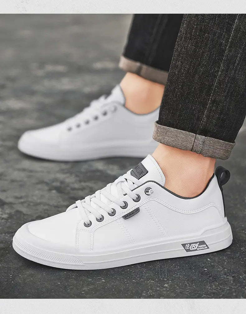 Men’s white minimalist leather casual sneakers with black accents and silver eyelets featuring a sleek design and subtle branding on the side.