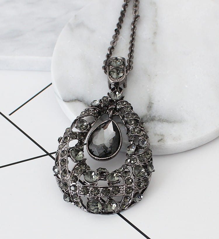 An ornate black rhinestone pendant necklace with a teardrop centerpiece and intricate filigree design featured as a blue teardrop filigree pendant Korean style sweater chain.