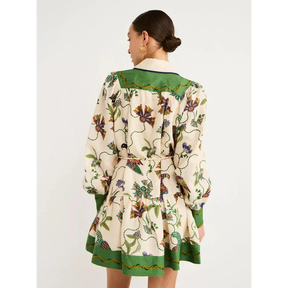 a cream-colored botanical print puff sleeve midi dress with vibrant floral and bird patterns and bold green trim along the collar cuffs and hem