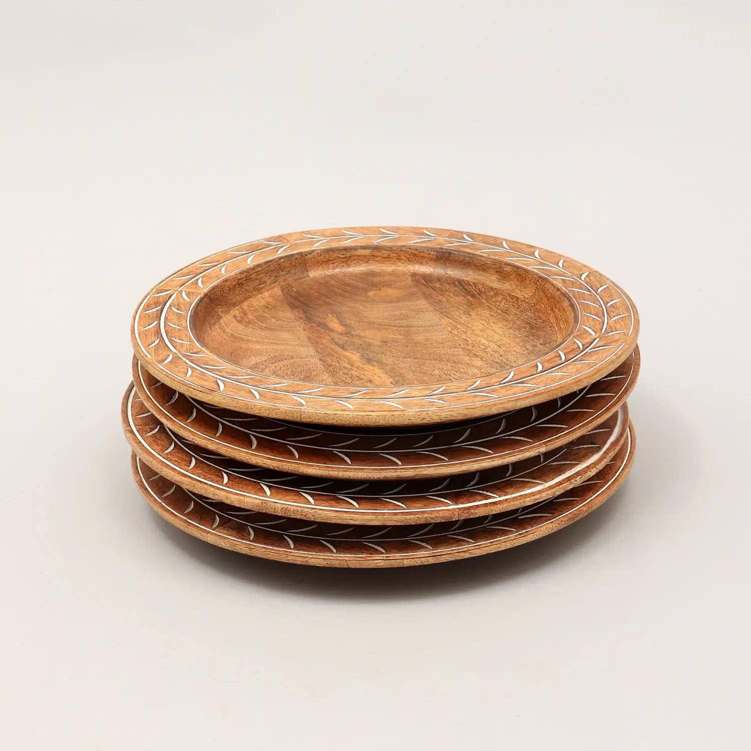 Set aus vier handgefertigten Holz-Tischsets mit einem Durchmesser von 13 Zoll, mit warmem natürlichem Finish und zarten weißen eingelegten Blattmustern entlang des Randes.