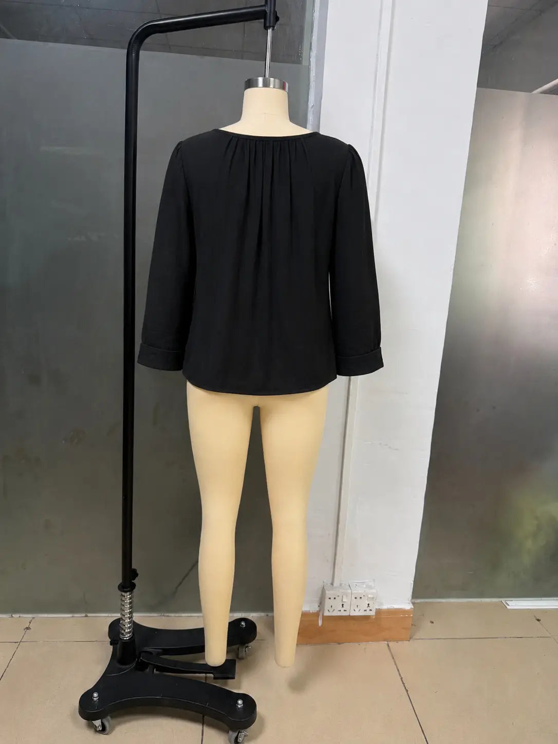 Une blouse ample en lin et coton pour femmes, noire, avec manches longues, encolure froncée et tissu souple s’écoulant.