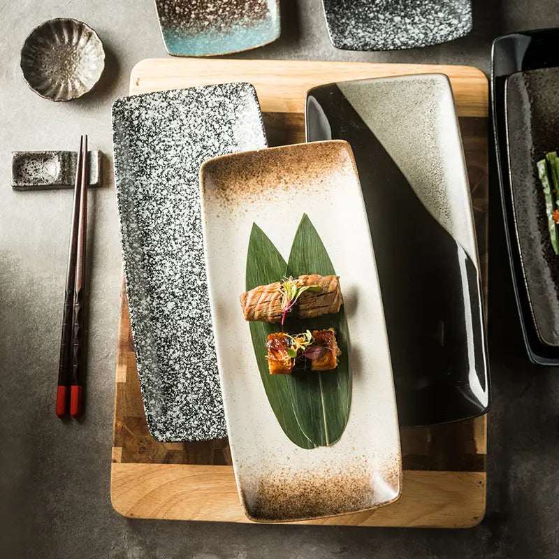 A rectangular Japanese ceramic sushi plate with speckled gray and white glaze and a subtle brown gradient along its edges.