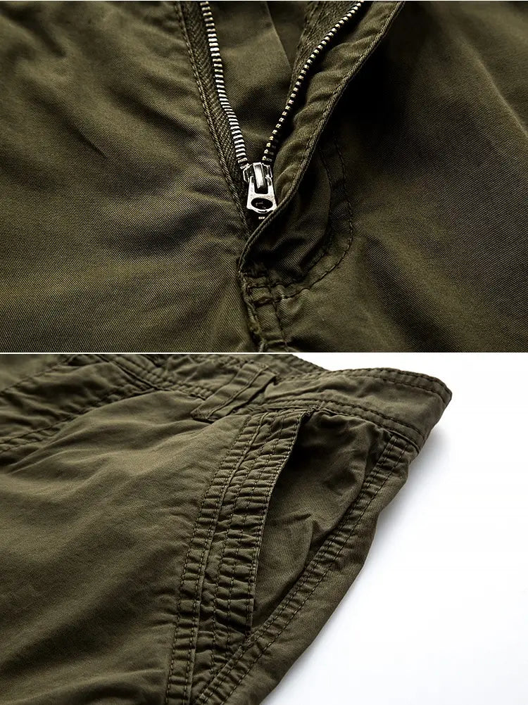 Bermudas cargo en coton vert olive pour hommes avec plusieurs poches, une fermeture éclair argentée, des poignets à cordon de serrage et des coutures renforcées.