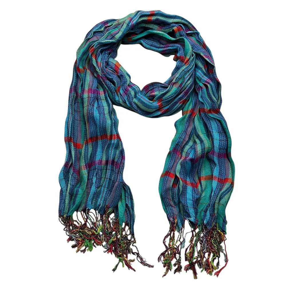 Une écharpe d’hiver bleu à jacquard texturé à motif écossais multicolore éclatant, avec des extrémités à franges, dans des nuances de bleu turquoise, rouge et violet.