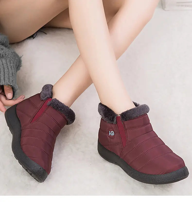 Bottines d’hiver imperméables en neige bordeaux matelassées, avec doublure intérieure moelleuse en fausse fourrure grise et semelle en caoutchouc noir pour une utilisation sur la neige.