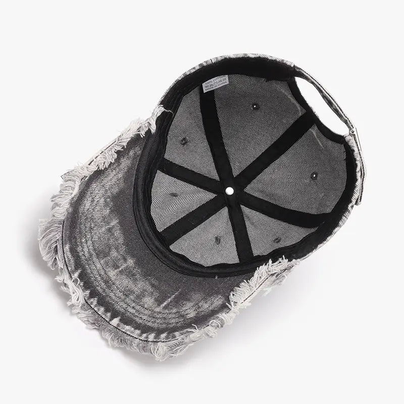 A distressed denim baseball cap in gray with frayed edges and a black interior.