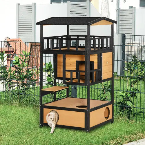 Black and light wood multi-level wooden outdoor cat house with a small white kitten peeking from the bottom compartment designed as a multi-level shelter.