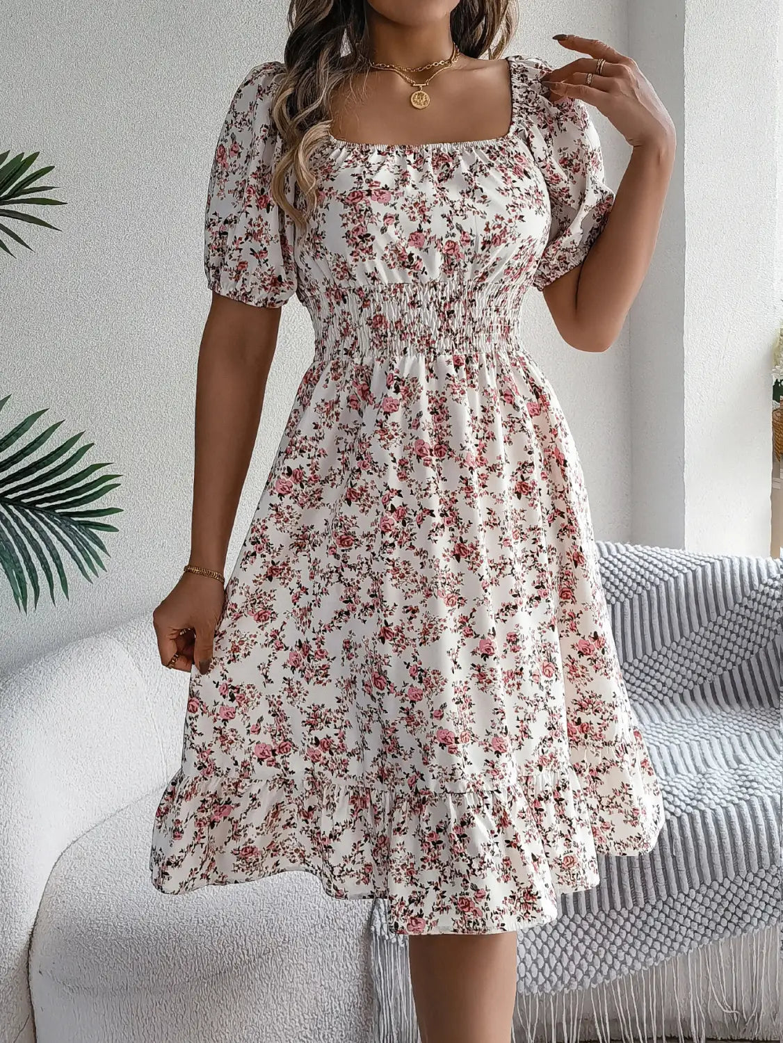 Robe d’été blanche à imprimé floral avec fleurs roses et vertes, encolure carrée, manches courtes bouffantes et taille smockée.