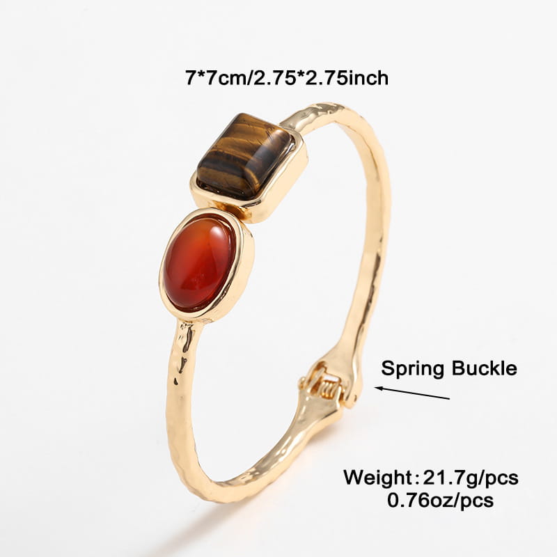 Vintage hammered gold bangle featuring a textured metal band with a spring buckle and two distinct gemstones a rectangular tiger’s eye and an oval carnelian set as multi gemstone accents.