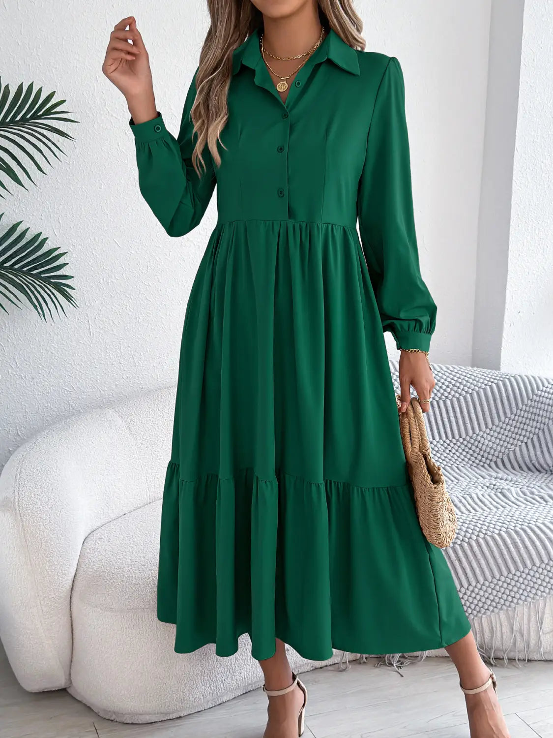 A woman wears a long sleeve emerald green button down midi dress with tiered ruffles at the hem.