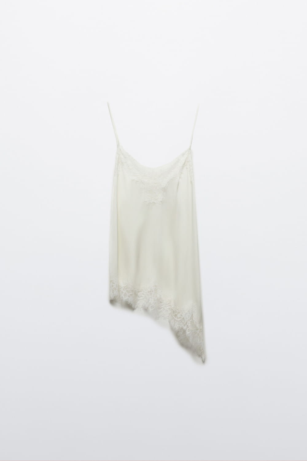 Ein zartes Camisole-Top aus Cremeweißem Satin mit Spitzenbesatz, dünnen Spaghettiträgern und einem fließenden asymmetrischen Saum.