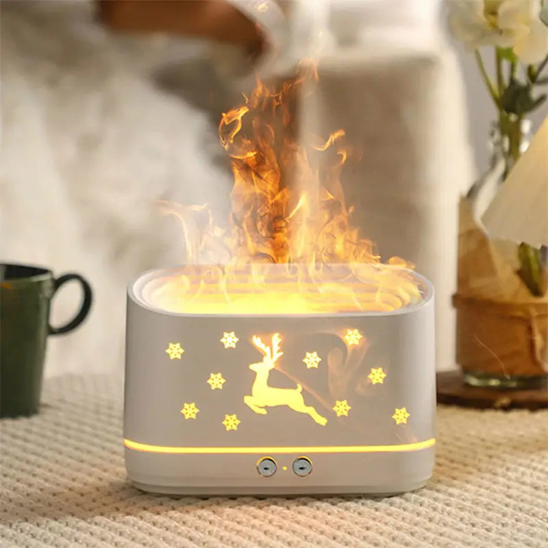 A white ceramic rectangular elk flame humidifier and oil diffuser with a glowing reindeer and snowflake design emitting warm light from its base.
