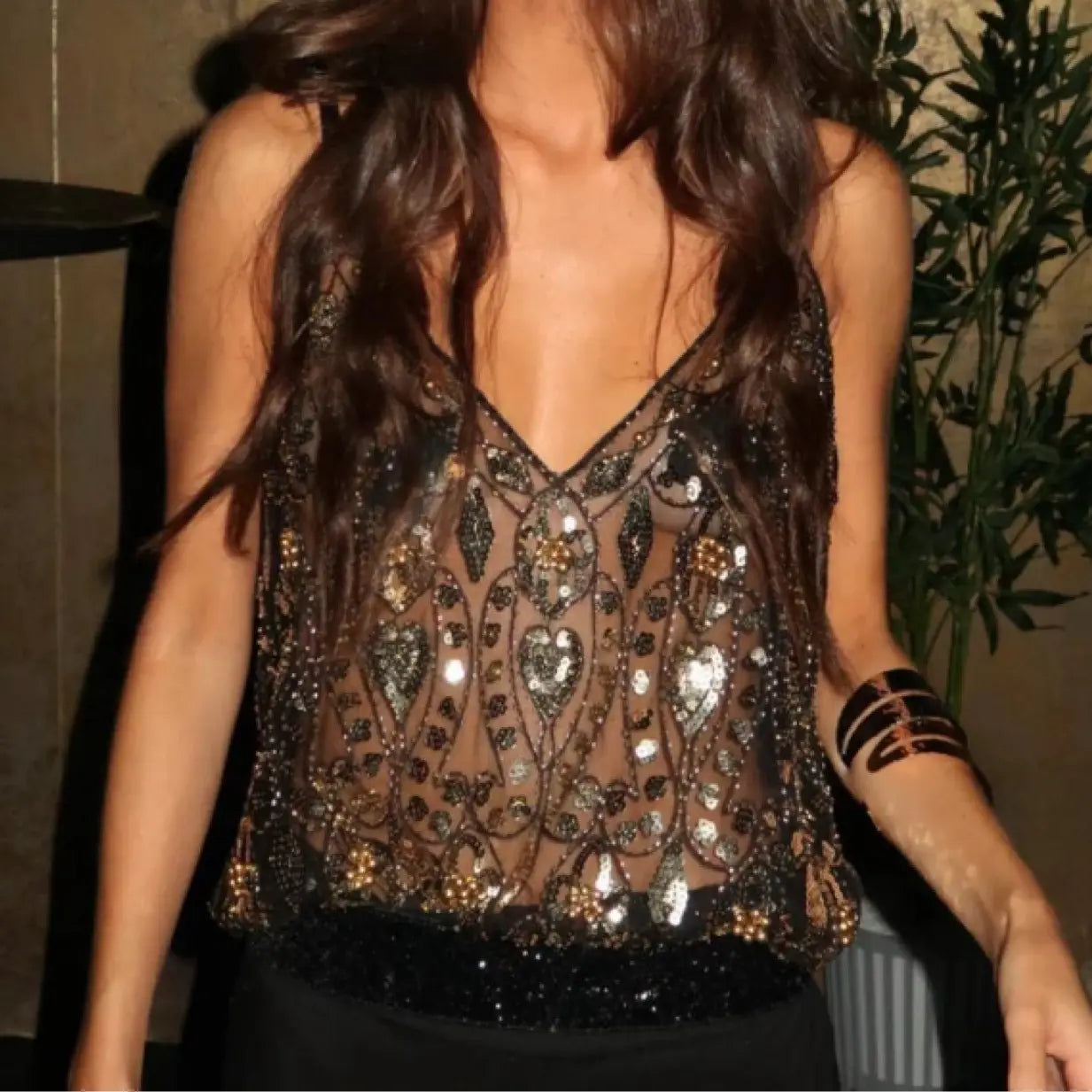 A sheer black sequin bead sling vest corset top adorned with intricate gold and silver heart and leaf pattern embellishments.