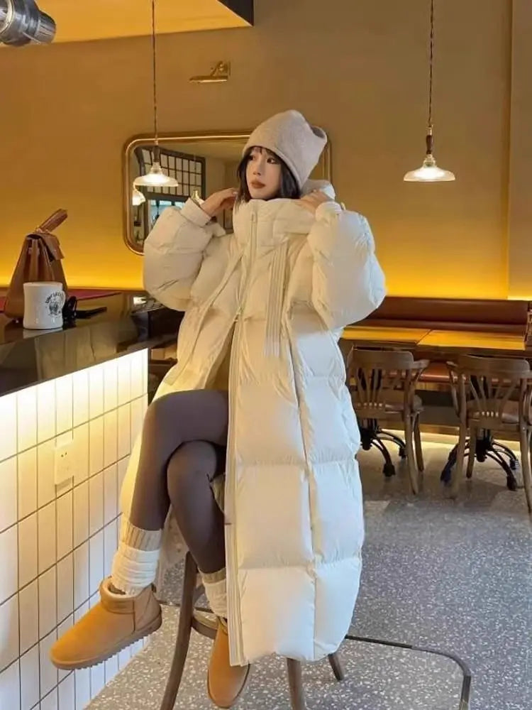 Cream-colored women long padded down jacket featuring a quilted design and high collar in a puffer coat style.