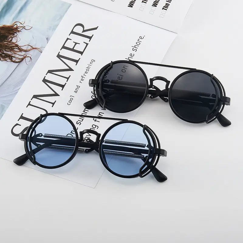 Gafas de sol steampunk con montura redonda negra, lentes oscuras y un diseño distintivo de doble resorte en las patillas.