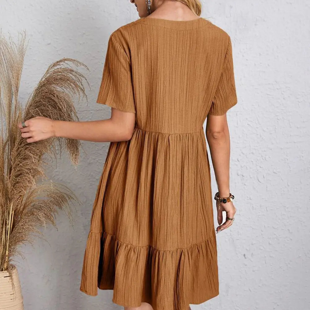 Une robe d’été souple côtelée beige à encolure en V pour femmes, à manches courtes volantées, avec une jupe à volants superposés.
