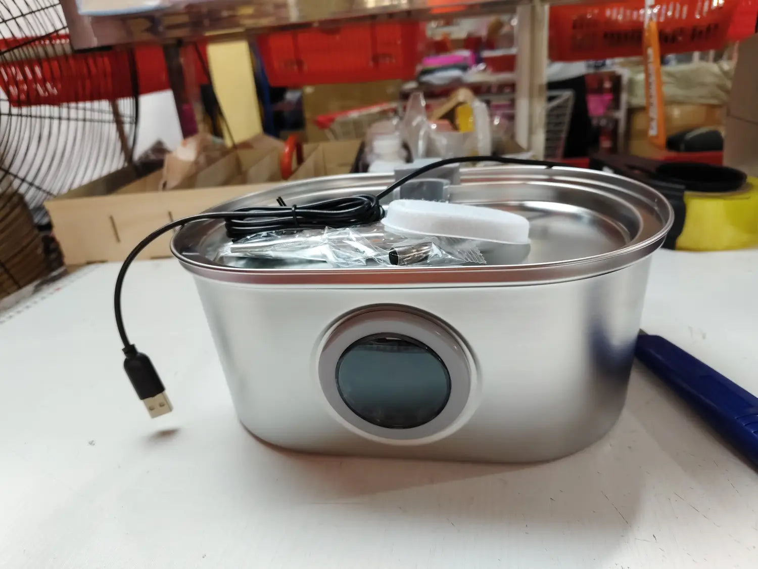 Silberner Edelstahl-Brunnen für Haustiere mit Filter, mit elektrischem Warmhaltefach und kreisförmiger Digitalanzeige sowie USB-Ladekabel.